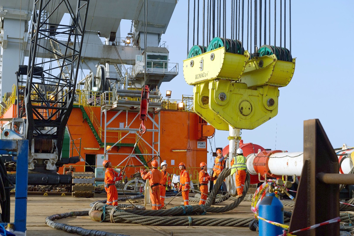Offshore heavy lift rigging crew coordinating a heavy lift operation using crane hooks and wire rope on an offshore platform.