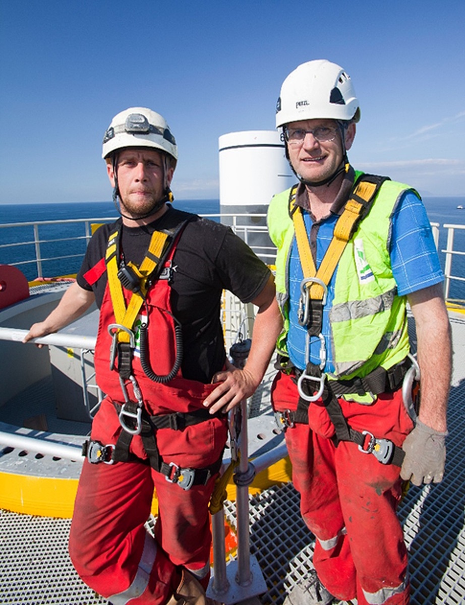 Offshore windfarm installation technicians wearing safety harnesses on platform